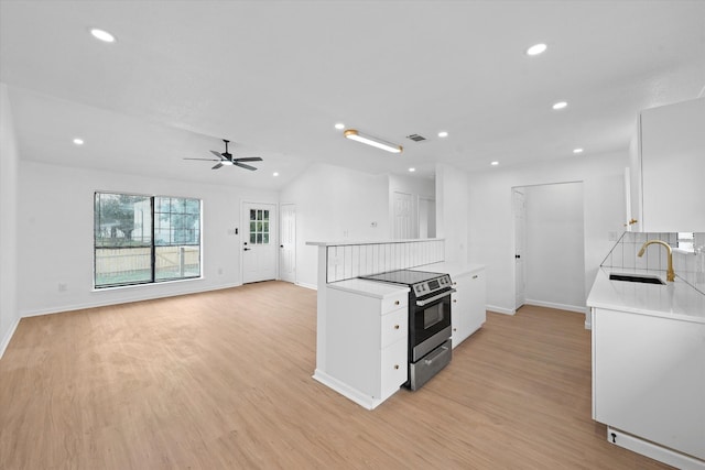 kitchen featuring light countertops, light wood-type flooring, a sink, and stainless steel range with electric stovetop