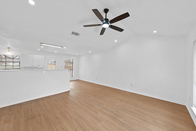 unfurnished living room featuring light wood-style floors, baseboards, visible vents, and vaulted ceiling