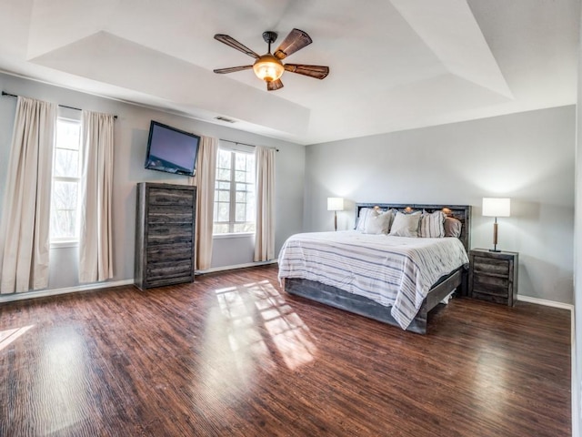 bedroom with baseboards, visible vents, a ceiling fan, a raised ceiling, and wood finished floors