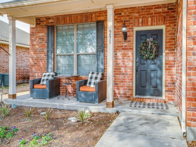 view of exterior entry featuring a porch and brick siding