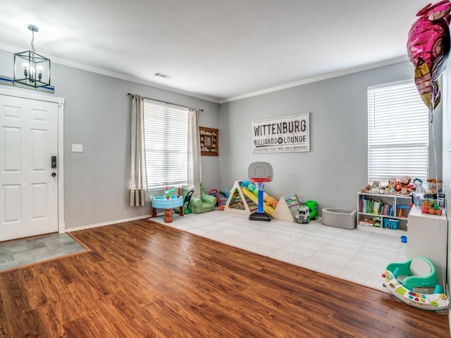 playroom featuring baseboards, visible vents, ornamental molding, wood finished floors, and a chandelier