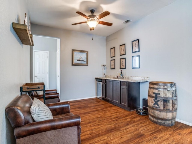 interior space with a ceiling fan, dark wood-style flooring, indoor wet bar, and visible vents