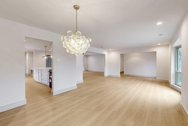 empty room featuring light wood-type flooring, baseboards, a chandelier, and recessed lighting