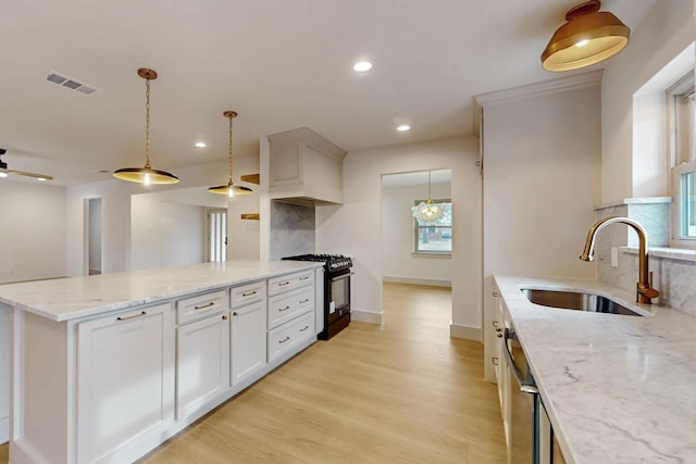 kitchen with light wood finished floors, tasteful backsplash, visible vents, black range with gas stovetop, and a sink