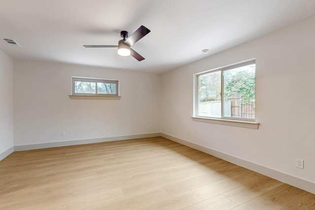 empty room with light wood-style floors, visible vents, ceiling fan, and baseboards