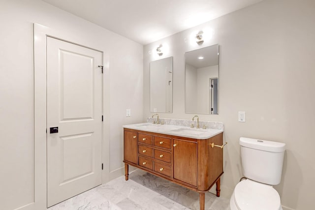 bathroom with marble finish floor, double vanity, a sink, and toilet