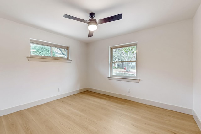 spare room with plenty of natural light, baseboards, light wood-style flooring, and a ceiling fan