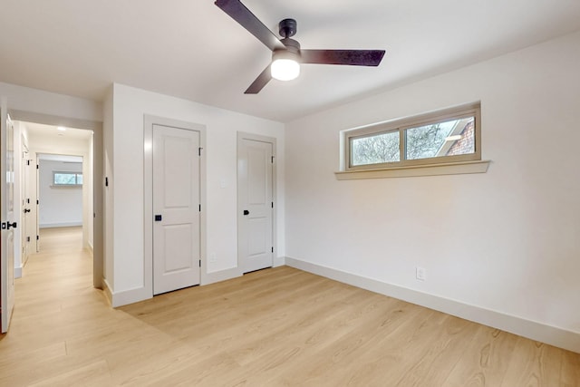 unfurnished bedroom with light wood finished floors, ceiling fan, baseboards, and two closets