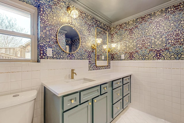 bathroom featuring a wainscoted wall, tile walls, toilet, and wallpapered walls