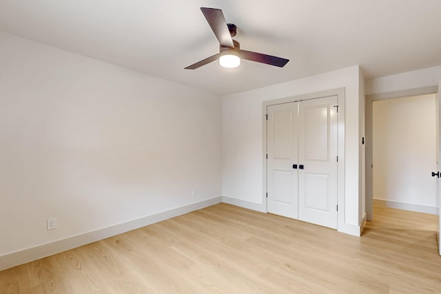 unfurnished bedroom with a closet, ceiling fan, light wood-style flooring, and baseboards