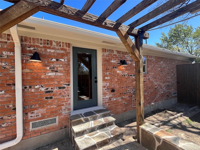 doorway to property featuring fence and brick siding