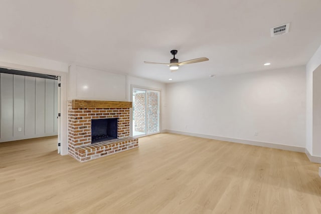 unfurnished living room featuring light wood finished floors, baseboards, a fireplace, and visible vents