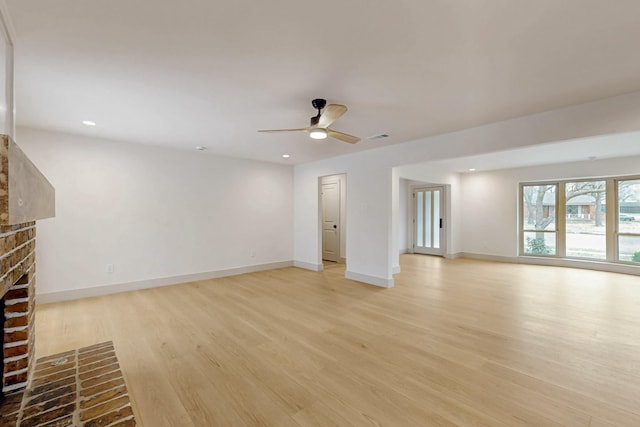 unfurnished living room featuring light wood finished floors, visible vents, baseboards, a ceiling fan, and a fireplace