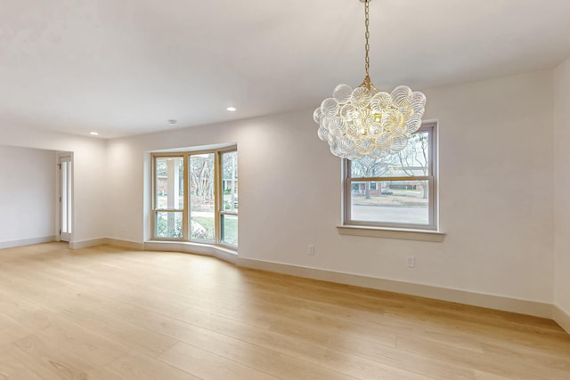 spare room featuring light wood finished floors, baseboards, a notable chandelier, and recessed lighting