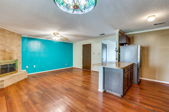 kitchen with a fireplace, open floor plan, freestanding refrigerator, dark wood-style floors, and crown molding