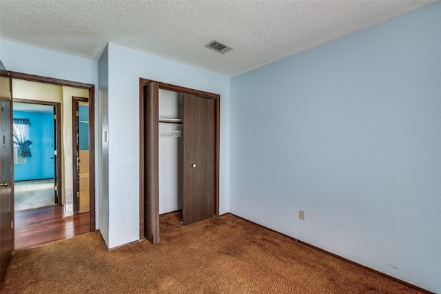 unfurnished bedroom with carpet floors, a closet, visible vents, and a textured ceiling