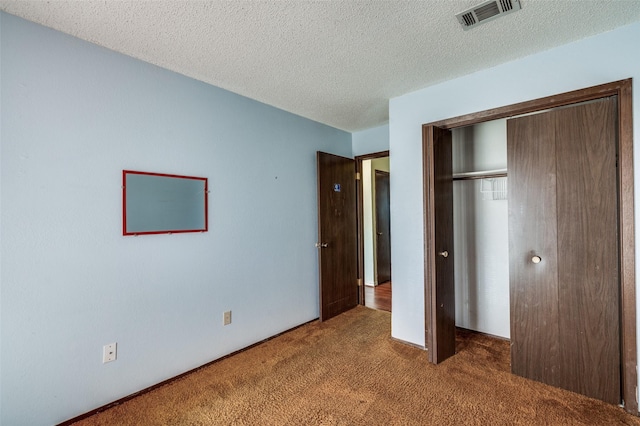 unfurnished bedroom featuring a textured ceiling, a closet, carpet flooring, and visible vents