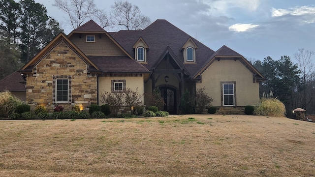 view of front of home with a shingled roof, stone siding, a front lawn, and stucco siding