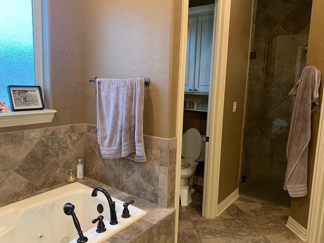 full bath featuring a jetted tub, a textured wall, a shower stall, and toilet