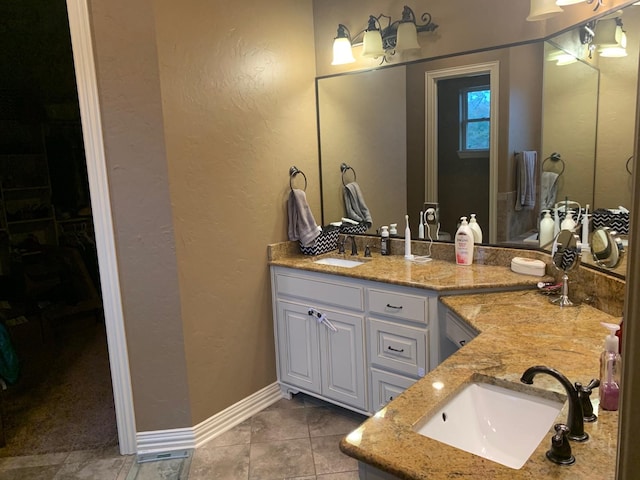 bathroom featuring double vanity, baseboards, a sink, and tile patterned floors