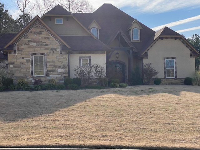 french country inspired facade with stone siding and a front yard