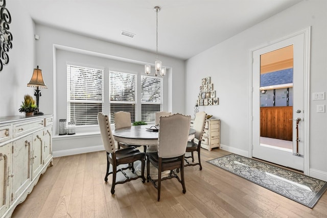 dining room featuring baseboards, light wood finished floors, and an inviting chandelier