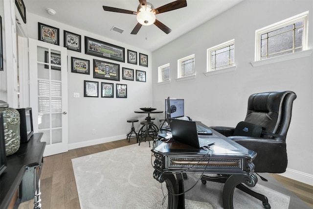 home office featuring a ceiling fan, baseboards, visible vents, and wood finished floors