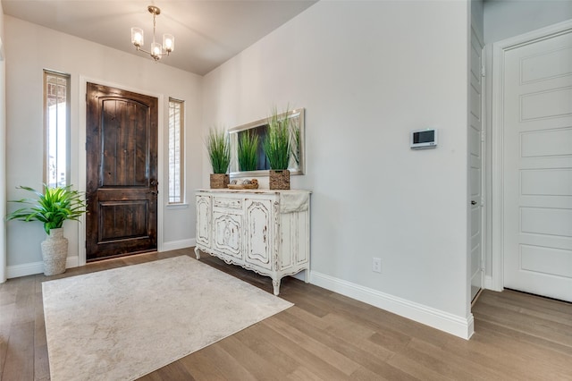 foyer featuring a notable chandelier, wood finished floors, and baseboards