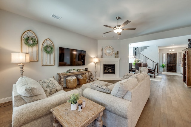 1612 Olympia Ave, Corinth, TX 76208 - living room featuring stairway, visible vents, ceiling fan, hardwood / wood-style flooring, and a glass covered fireplace