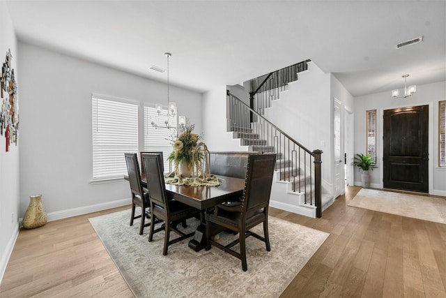 dining area featuring wood-type flooring, visible vents, and an inviting chandelier