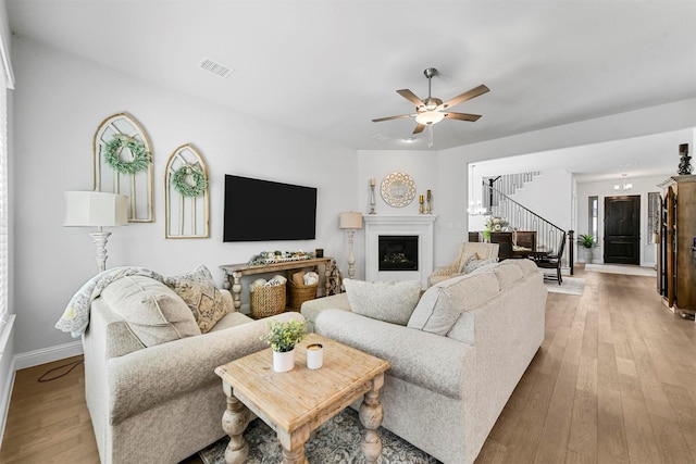 living room with stairs, visible vents, a fireplace, and hardwood / wood-style floors