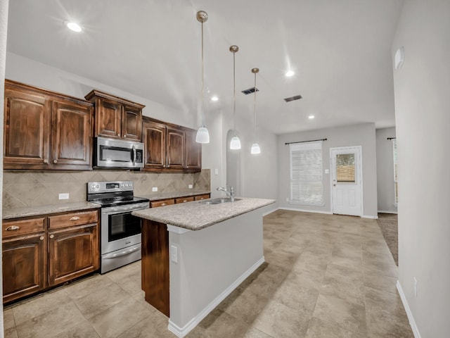 kitchen with a sink, visible vents, appliances with stainless steel finishes, backsplash, and a center island with sink