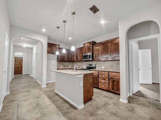 kitchen featuring a kitchen island with sink, stainless steel appliances, a sink, tasteful backsplash, and pendant lighting