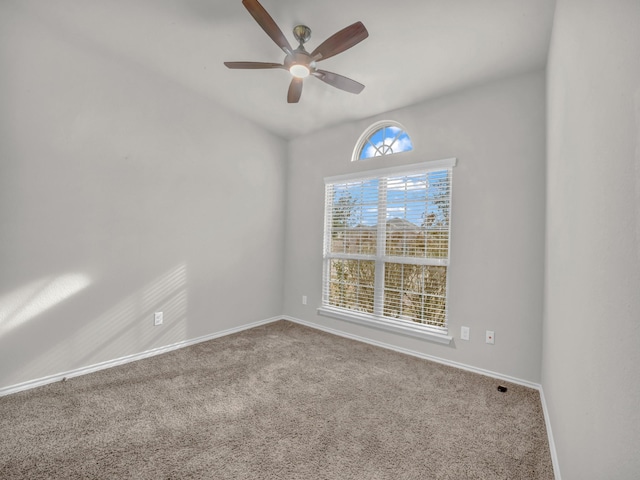 carpeted spare room featuring a ceiling fan and baseboards