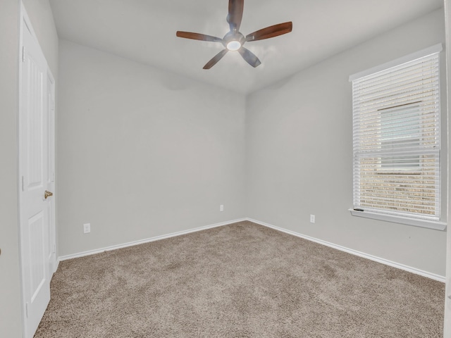 carpeted spare room featuring a ceiling fan and baseboards