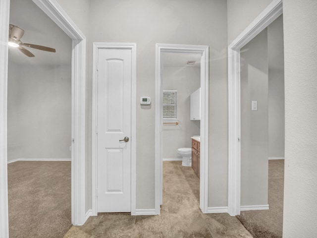 hallway featuring light carpet and baseboards