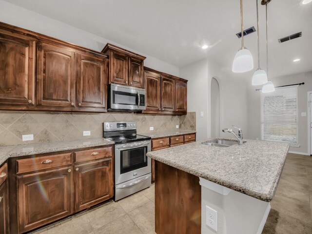 kitchen featuring arched walkways, light stone counters, a sink, appliances with stainless steel finishes, and tasteful backsplash