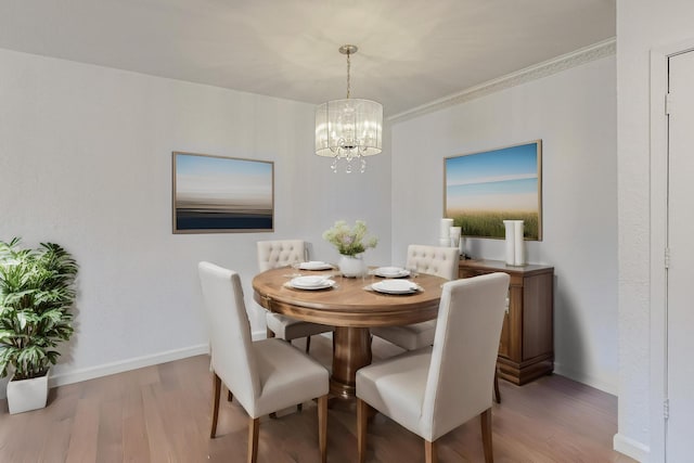 dining area with an inviting chandelier, crown molding, baseboards, and wood finished floors