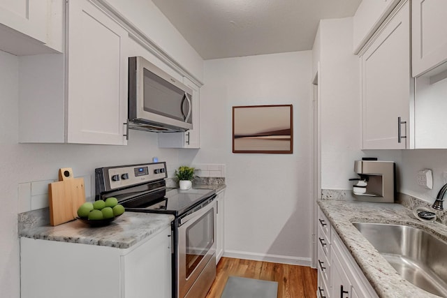 kitchen with light wood-style floors, white cabinetry, appliances with stainless steel finishes, and a sink