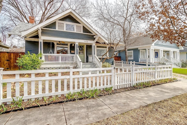 bungalow-style home with a porch, a fenced front yard, and a shingled roof