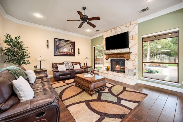 living room featuring plenty of natural light, wood-type flooring, visible vents, and a stone fireplace