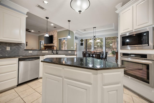 kitchen with a kitchen island, a sink, visible vents, appliances with stainless steel finishes, and decorative backsplash