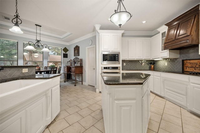 kitchen featuring a center island, a tray ceiling, stainless steel appliances, backsplash, and ornamental molding