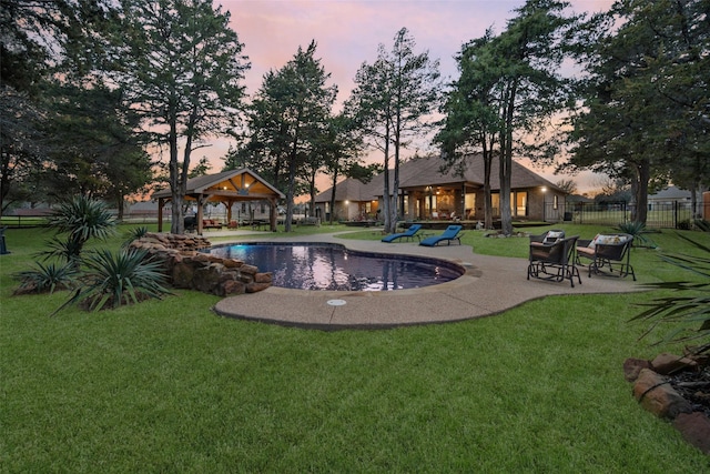 pool at dusk with a lawn, a patio, a gazebo, and fence