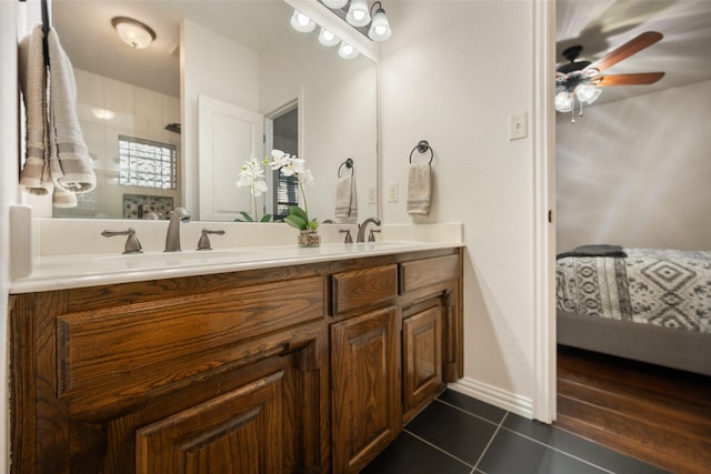 ensuite bathroom with double vanity, a ceiling fan, connected bathroom, a sink, and tile patterned floors