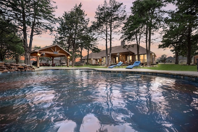 view of swimming pool with fence and a gazebo