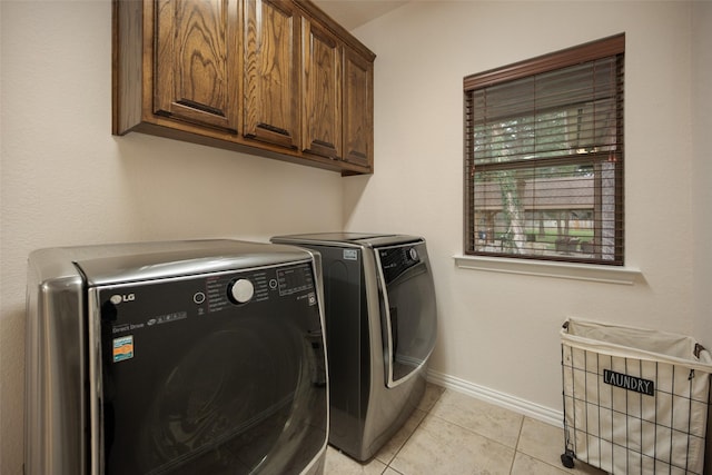 laundry area featuring washing machine and dryer, cabinet space, baseboards, and light tile patterned floors