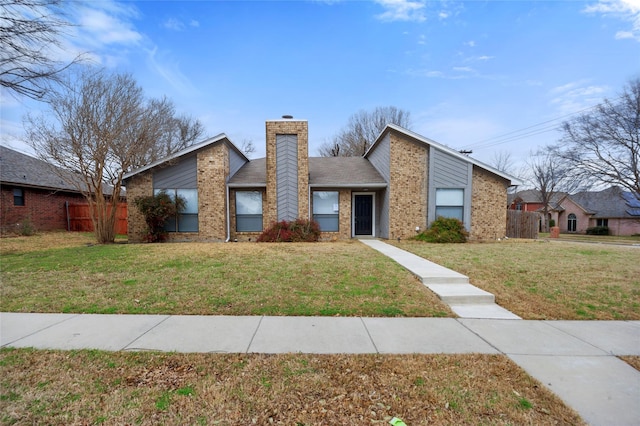 mid-century home with brick siding, a chimney, and a front lawn