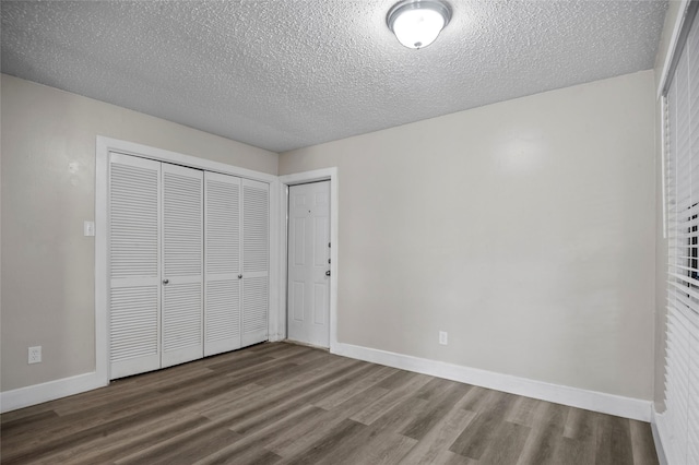 unfurnished bedroom with a closet, a textured ceiling, baseboards, and wood finished floors