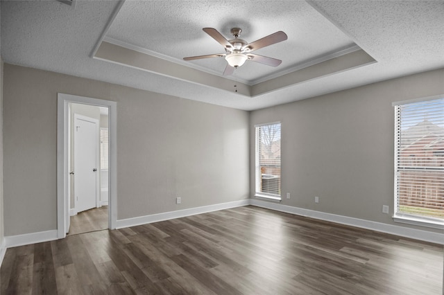 unfurnished room with a textured ceiling, a ceiling fan, a raised ceiling, and dark wood-type flooring